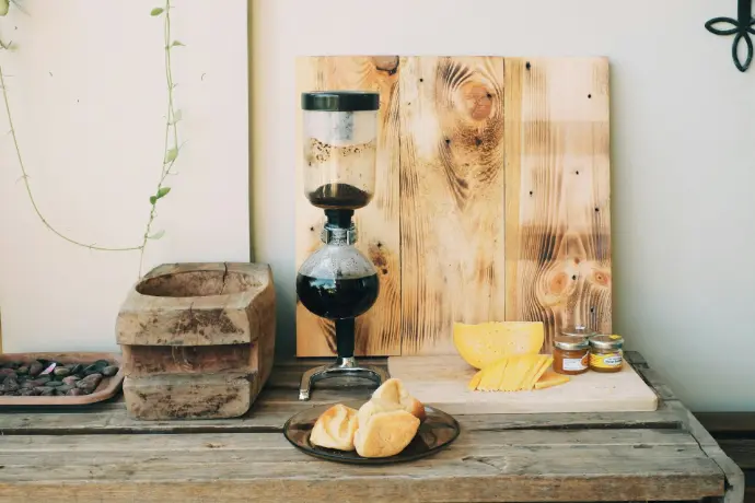 bread on brown wooden chopping board beside black and clear glass vase